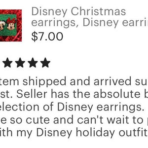 May include: A pair of red and green Christmas earrings featuring Mickey Mouse and Minnie Mouse. The earrings are on a red and green background.