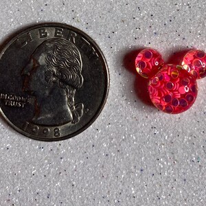 Op de afbeelding: Roze Mickey Mouse hoofd resin charme met iriserende glitter ingebed in de hars. De charme is ongeveer de grootte van een Nederlandse 2 euro munt.