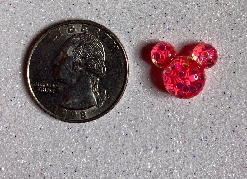 Op de afbeelding: Roze Mickey Mouse hoofd resin charme met iriserende glitter ingebed in de hars. De charme is ongeveer de grootte van een Nederlandse 2 euro munt.