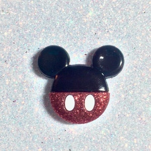 May include: A red and black glitter Mickey Mouse head with white eyes.