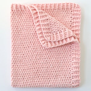 May include: A soft pink crocheted baby blanket with a textured, fuzzy surface.