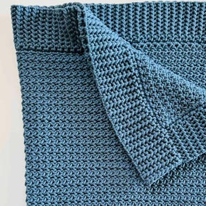 May include: A blue crocheted blanket folded in half, showing the textured stitch pattern.