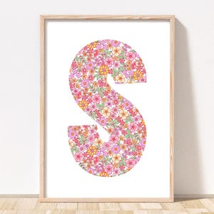 May include: A framed print of the letter "S" made up of pink, orange, and green flowers on a white background.