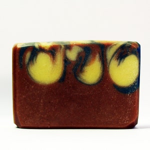 Puede incluir: Una barra de jab&oacute;n rectangular con una base marr&oacute;n y remolinos de amarillo y azul.