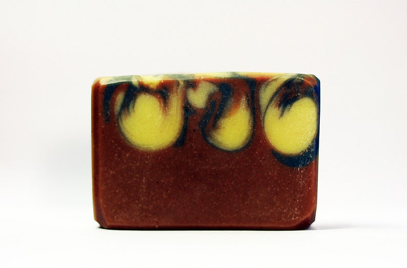 Puede incluir: Una barra de jab&oacute;n rectangular con una base marr&oacute;n y remolinos de amarillo y azul.