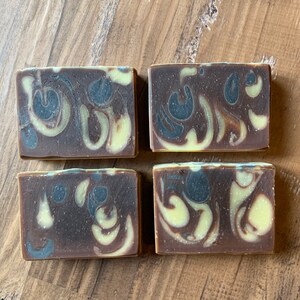 Puede incluir: Cuatro barras de jab&oacute;n hecho a mano con un patr&oacute;n de remolino marr&oacute;n y amarillo. El jab&oacute;n est&aacute; hecho con ingredientes naturales y es perfecto para pieles sensibles.