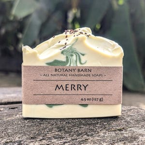 May include: A bar of white soap with green and brown swirls. The soap is labelled "Botany Barn" and "Merry" with a weight of 127 g (4.5 oz).