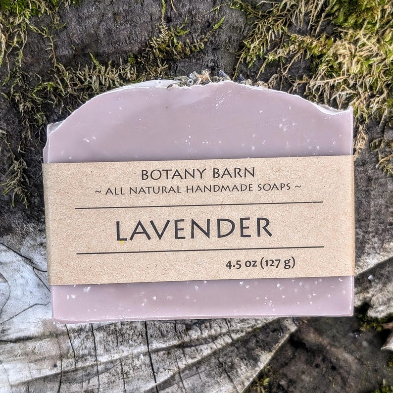 May include: A lavender-colored bar of soap with a brown label that reads "Botany Barn ~ All Natural Handmade Soaps ~ Lavender 4.5 oz (127 g)"