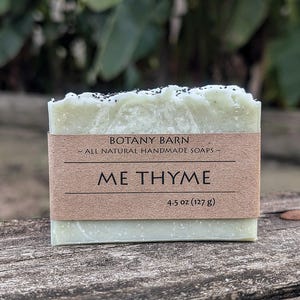 May include: A green bar of soap with black specks, labeled "BOTANY BARN ~ALL NATURAL HANDMADE SOAPS~ ME THYME 4.5 oz (127 g)"