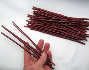 May include: A bundle of approximately 50 thin, red, wooden sticks. The sticks are about 6 inches long and are bundled together in a loose pile.