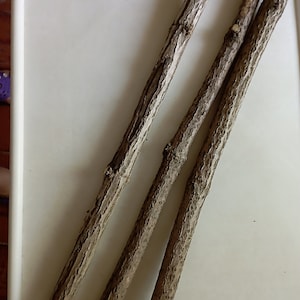 May include: Three brown wooden sticks on a white surface.