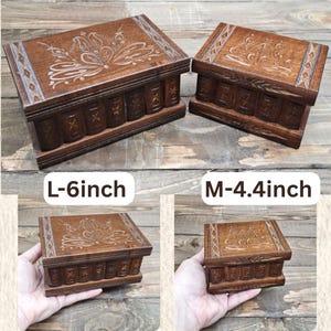 May include: Two rectangular wooden puzzle boxes with dark brown finishes and carved floral patterns on the lids. The larger box is labeled L-6inch and the smaller box is labeled M-4.4inch. Both feature vertical carved details along the front side.