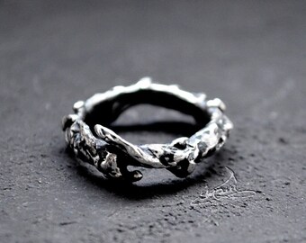 Può includere: Un anello d'argento con un design attorcigliato e testurizzato che ricorda un ramo.
