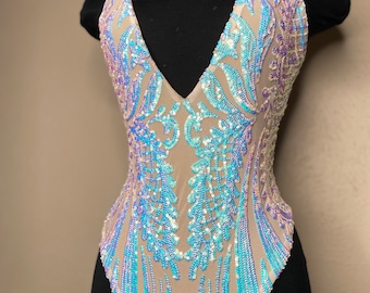 May include: A nude-colored bodysuit with a plunging neckline and iridescent blue and purple sequins in a floral pattern.