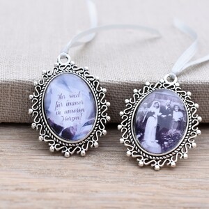 Könnte beinhalten: Zwei silberne ovale Bilderrahmen mit weißen Schleifen zum Aufhängen. Ein Rahmen zeigt ein Schwarzweißfoto einer Hochzeitsgesellschaft. Der andere Rahmen hat ein Blumenmuster und den Text "Ihr seid für immer in unseren Herzen!"