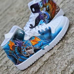 May include: A pair of white high-top sneakers with a custom hand-painted design. The design features a blue and orange dragon with a fierce expression. The sneakers are a popular choice for collectors and fans of custom footwear.