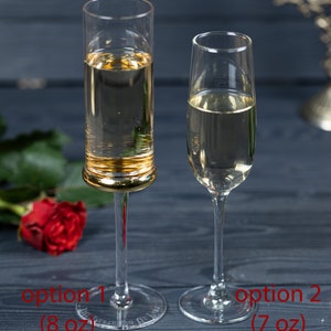 May include: Two champagne flutes, one with a gold rim, filled with a clear sparkling beverage. The flute on the left is labeled "option 1 (8 oz)" and the flute on the right is labeled "option 2 (7 oz)".
