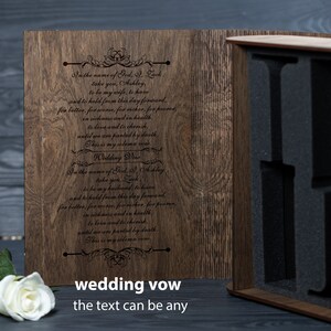 May include: A wooden box with a hinged lid, engraved with wedding vows. The box is open, revealing a black foam interior with cutouts for holding items. The text on the box reads: "In the name of God, I, Lack, take you, Ashley, to be my wife, to have and to hold from this day forward, for better, for worse, for richer, for poorer, in sickness and in health, to love and to cherish, until we are parted by death. This is my solemn vow. Wedding Vow"