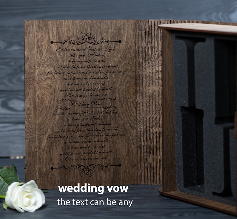 May include: A wooden box with a hinged lid, engraved with wedding vows. The box is open, revealing a black foam interior with cutouts for holding items. The text on the box reads: "In the name of God, I, Lack, take you, Ashley, to be my wife, to have and to hold from this day forward, for better, for worse, for richer, for poorer, in sickness and in health, to love and to cherish, until we are parted by death. This is my solemn vow. Wedding Vow"