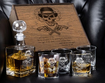 May include: A wooden box with a skull and crossbones design engraved on the lid. The box contains a glass decanter and four glasses, all with the same skull and crossbones design. The text on the box reads: "A well regulated Militia, being necessary to the security of a free State, the right of the people to keep and bear Arms, shall not be infringed. December 15, 1791."