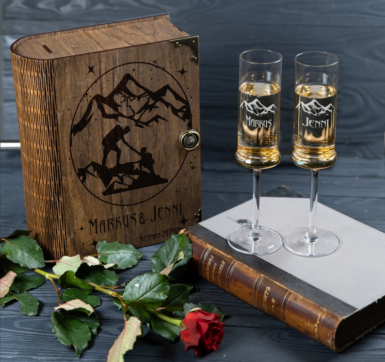 May include: A wooden box with a mountain scene and the text "Markus & Jenni" engraved on the front. Two champagne flutes with the names "Markus" and "Jenni" engraved on them are in the foreground.
