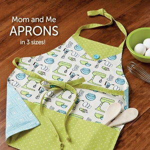 May include: A green and white apron with a mixer and bowl pattern. The apron has a pocket and ties. The text "Mom and Me Aprons in 3 sizes!" is at the top of the image. The text "BONUS! includes Chenille Hotpad!" is at the bottom of the image. The text "ATK-176" is in the bottom right corner of the image.