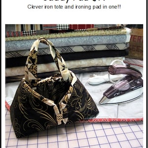 May include: A black and gold fabric tote bag with a heat-resistant lining. The tote opens up to become a 6-8 1/4 inch ironing pad. "Caddy Pad Jr." and "Clever iron tote and ironing pad in one!!" are written in blue text on a white background.