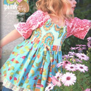 May include: A girl wearing a colorful, patterned dress with a ruffled bottom. The dress has a gathered bodice and short sleeves. The dress is called "the Mia top No. 14".