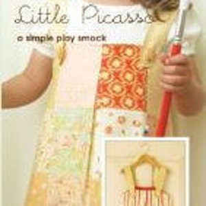 May include: A yellow and red patchwork play smock with a pocket and a ruffle. The smock is designed for children to wear while painting or doing other messy activities. The text "Little Picasso" is written on the smock.