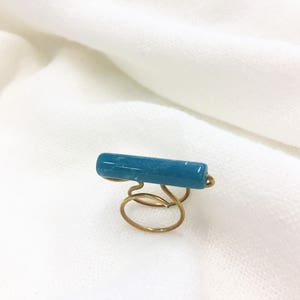 Handmade ring with bronze wire and blue cylindrical acrylic bead.
