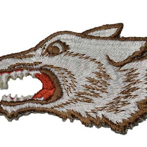May include: White embroidered wolf head patch with brown outline and red teeth. The wolf's mouth is open and its eyes are closed.