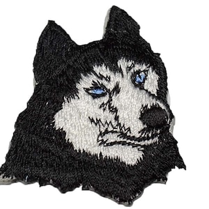 May include: Embroidered patch of a black and white husky dog with blue eyes. The dog is looking to the right and has a serious expression.