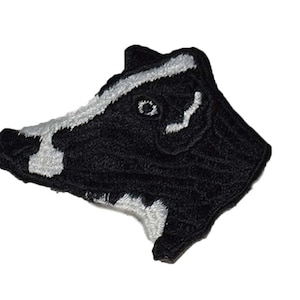 May include: Black and white embroidered patch of a badger's head.