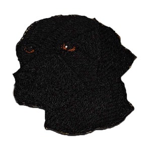 May include: Black embroidered patch of a dog's head with orange eyes.