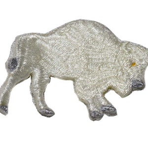 May include: Embroidered patch in the shape of a white bison, with gray detailing on the hooves, tail, and a spot on the back. The bison has a yellow eye and is walking to the left. The patch is likely for clothing or accessories.