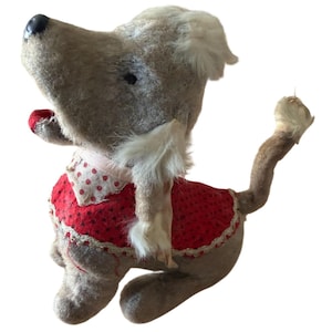 May include: A vintage stuffed dog toy with a light brown body, black eyes, and a red polka-dot outfit. The dog has a white fur collar and a tail. The toy is made of a soft, plush material.