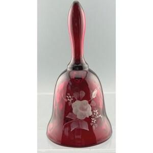 Puede incluir: Una campana de cristal de color rojo rubí intenso con un diseño floral grabado en transparente en el exterior. La campana tiene un mango liso y alargado y una base acampanada, mostrando una calidad translúcida que permite el paso de luz.