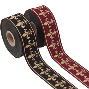 Könnte beinhalten: Zwei Spulen dekoratives Band. Eine ist schwarz mit einem goldenen Fleur-de-Lis-Muster, die andere bordeauxrot mit einem goldenen Fleur-de-Lis-Muster. Das Band wird wahrscheinlich für Bastelarbeiten, Geschenkverpackungen oder Verzierungen verwendet.