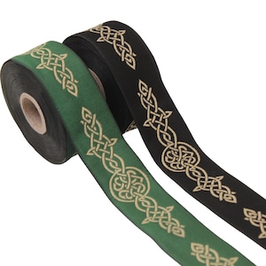Puede incluir: Dos rollos de cinta decorativa. Uno es verde con un diseño de nudo celta dorado, el otro negro con un diseño de nudo celta dorado. Las cintas están desenrolladas, mostrando el intrincado patrón.
