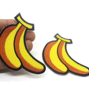 May include: Two embroidered iron-on patches of yellow and orange bananas with black outlines.