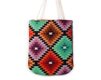 May include: A colorful tote bag with a geometric pattern in shades of green, orange, red, purple, and black. The bag has white cotton straps.