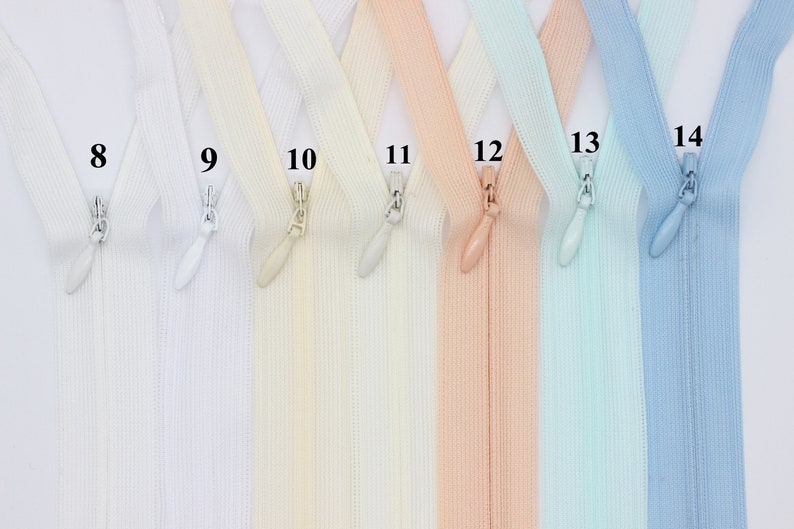 May include: A set of seven zipper tapes in various colors, including white, cream, peach, light blue, and blue. The zippers are labeled with numbers 8 through 14.