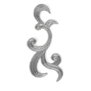 May include: A silver embroidered applique with a swirling, ornate design. The decorative patch features a textured surface and is ideal for embellishing clothing or craft projects. The design is symmetrical and elegant.