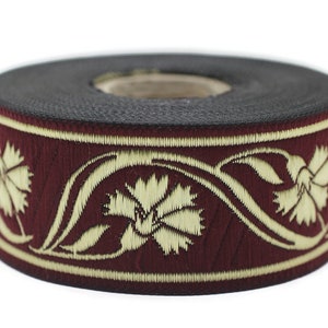May include: A roll of decorative ribbon featuring a burgundy background with an embroidered floral design in cream. The ribbon is approximately 1 inch wide and is suitable for various craft projects.