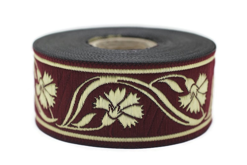 May include: A roll of decorative ribbon featuring a burgundy background with an embroidered floral design in cream. The ribbon is approximately 1 inch wide and is suitable for various craft projects.