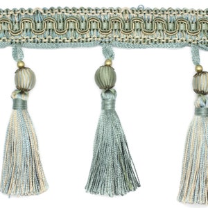 May include: A light blue tassel trim with a beaded accent. The trim has a woven design and is made of a soft, silky material.