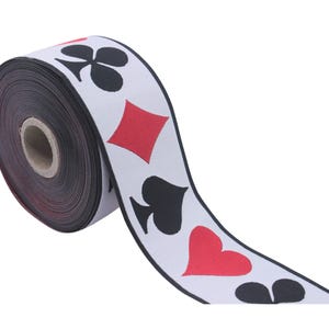 May include: A roll of white ribbon with black and red playing card symbols printed on it. The symbols include hearts, spades, diamonds, and clubs.