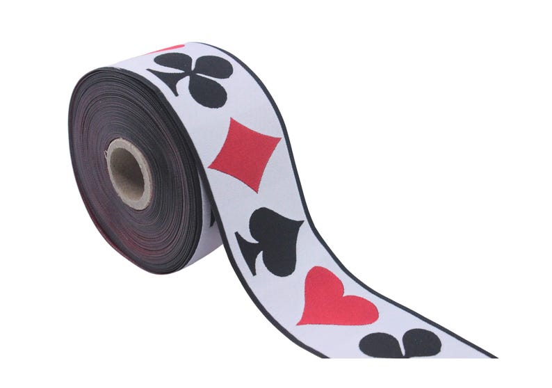 May include: A roll of white ribbon with black and red playing card symbols printed on it. The symbols include hearts, spades, diamonds, and clubs.