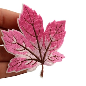 Op de afbeelding: Roze geborduurde esdoornblad patch met bruine aderen.