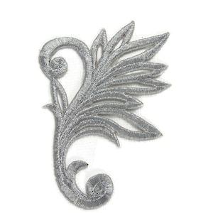 May include: Silver embroidered floral applique with a delicate design. This intricate embellishment features a swirling stem and a cluster of leaves.
